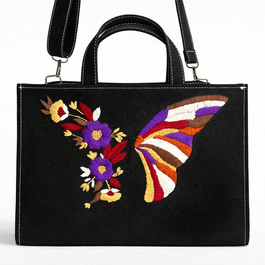 Black handbag with colorful butterfly and floral design on a white background