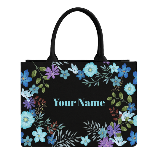 Black tote bag with floral design and space for personalization on a white background