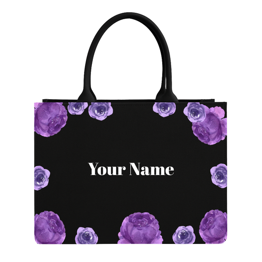 Black tote bag with purple floral design and space for personalization on a white background