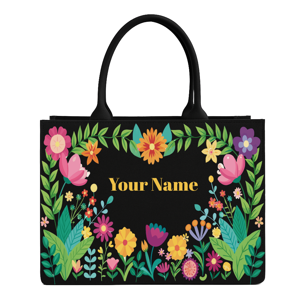 Black tote bag with colorful floral design and space for personalization on a white background