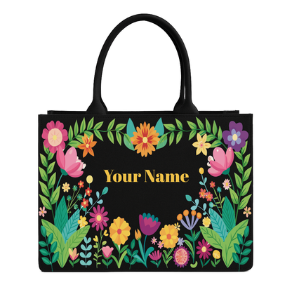 Black tote bag with colorful floral design and space for personalization on a white background