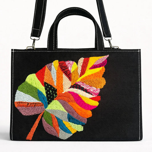Black handbag with a colorful embroidered leaf design on a white background