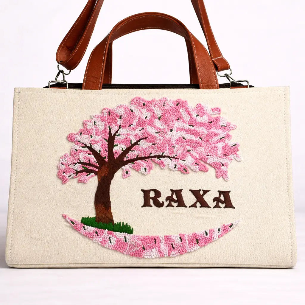 Handbag with cherry blossom design and 'RAXA' branding on a white background
